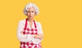 Senior grey-haired woman wearing apron skeptic and nervous, disapproving expression on face with crossed arms