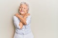 Senior grey-haired woman wearing casual clothes hugging oneself happy and positive, smiling confident Royalty Free Stock Photo