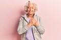 Senior grey-haired woman wearing casual sporty clothes smiling with hands on chest with closed eyes and grateful gesture on face Royalty Free Stock Photo