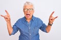 Senior grey-haired woman wearing denim shirt and glasses over isolated white background shouting with crazy expression doing rock Royalty Free Stock Photo
