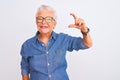 Senior grey-haired woman wearing denim shirt and glasses over isolated white background smiling and confident gesturing with hand Royalty Free Stock Photo