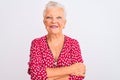 Senior grey-haired woman wearing red casual jacket standing over isolated white background happy face smiling with crossed arms Royalty Free Stock Photo