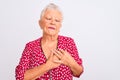 Senior grey-haired woman wearing red casual jacket standing over isolated white background smiling with hands on chest with closed Royalty Free Stock Photo