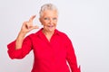 Senior grey-haired woman wearing red casual shirt standing over isolated white background smiling and confident gesturing with Royalty Free Stock Photo