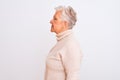 Senior grey-haired woman wearing turtleneck sweater standing over isolated white background looking to side, relax profile pose