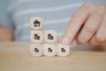 hand holding cash icon on wooden cube block with house symbol on top for retirement, saving, pension concept