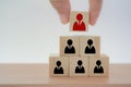 Hand putting wooden block on top stack of cube, pyramid shape, for human resource management and recruitment business concept Royalty Free Stock Photo