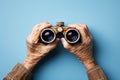 Senior Hands Hold Vintage Binoculars, Exploring The Future Against A Blue Background Royalty Free Stock Photo