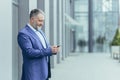 Senior businessman man stands near the office center and waits for customers holds the phone Royalty Free Stock Photo