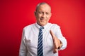 Senior handsome businessman wearing elegant tie standing over isolated red background smiling friendly offering handshake as Royalty Free Stock Photo