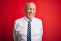 Senior handsome businessman wearing elegant tie standing over isolated red background winking looking at the camera with sexy Royalty Free Stock Photo