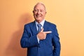 Senior handsome grey-haired businessman wearing elegant suit over yellow background smiling cheerful pointing with hand and finger Royalty Free Stock Photo