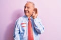 Senior handsome grey-haired businessman wearing tie and shirt with name presentation sticker smiling with hand over ear listening