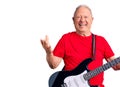 Senior handsome grey-haired man playing electric guitar celebrating victory with happy smile and winner expression with raised Royalty Free Stock Photo