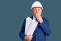 Senior handsome grey-haired man wearing architect hardhat holding blueprints covering mouth with hand, shocked and afraid for Royalty Free Stock Photo