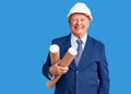 Senior handsome grey-haired man wearing architect hardhat holding blueprints looking positive and happy standing and smiling with Royalty Free Stock Photo