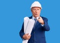 Senior handsome grey-haired man wearing architect hardhat holding blueprints pointing with finger to the camera and to you, Royalty Free Stock Photo