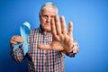 Senior handsome hoary man holding blue cancer ribbon symbol over isolated background with open hand doing stop sign with serious Royalty Free Stock Photo