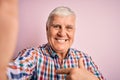 Senior handsome hoary man wearing casual shirt making selfie by the camera with surprise face pointing finger to himself Royalty Free Stock Photo