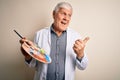 Senior handsome hoary painter man painting using brush and palette with colors pointing and showing with thumb up to the side with Royalty Free Stock Photo