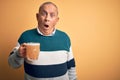 Senior handsome man drinking jar of beer standing over isolated yellow background In shock face, looking skeptical and sarcastic, Royalty Free Stock Photo