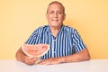Senior handsome man with gray hair eating sweet watermelon slice looking positive and happy standing and smiling with a confident Royalty Free Stock Photo