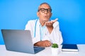 Senior handsome man with gray hair wearing doctor uniform working using computer laptop looking at the camera blowing a kiss with Royalty Free Stock Photo