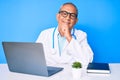 Senior handsome man with gray hair wearing doctor uniform working using computer laptop looking confident at the camera with smile Royalty Free Stock Photo