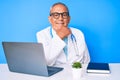 Senior handsome man with gray hair wearing doctor uniform working using computer laptop looking confident at the camera smiling Royalty Free Stock Photo