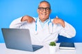 Senior handsome man with gray hair wearing doctor uniform working using computer laptop looking confident with smile on face, Royalty Free Stock Photo