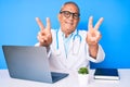 Senior handsome man with gray hair wearing doctor uniform working using computer laptop smiling looking to the camera showing Royalty Free Stock Photo