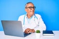 Senior handsome man with gray hair wearing doctor uniform working using computer laptop smiling looking to the side and staring Royalty Free Stock Photo