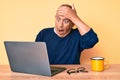 Senior handsome man with gray hair working at the office with laptop stressed and frustrated with hand on head, surprised and Royalty Free Stock Photo