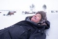 Senior handsome man in warm clothes and hat lying on snow and dreaming Royalty Free Stock Photo