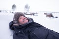 Senior handsome man in warm clothes and hat lying on snow and dreaming Royalty Free Stock Photo