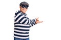 Senior handsome man wearing burglar mask and t-shirt inviting to enter smiling natural with open hand Royalty Free Stock Photo