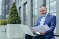 Senior handsome successful male engineer architect in suit works with laptop, documents, drawings Royalty Free Stock Photo