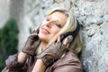 Senior handsome woman near a stone wall with headphone