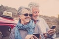 Senior happy cheerful old caucasian couple use together modern online technology smart phone to share and send contents on the