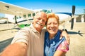Senior happy couple taking selfie with private ultralight plane
