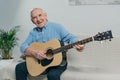 Senior happy man plays acoustic guitar while sitting on sofa Royalty Free Stock Photo