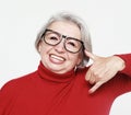 Senior happy woman wearing red sweater and glasses is making a call me gesture Royalty Free Stock Photo