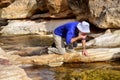 Senior hiker drinks water from mountain river