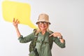 Senior hiker woman wearing canteen holding speech bubble over isolated white background with surprise face pointing finger to Royalty Free Stock Photo