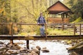 Senior hiker woman 60 years old with backpack crossing footbridge across forest river. Royalty Free Stock Photo