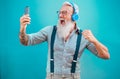 Senior hipster man using smartphone app for creating playlist with rock music - Trendy tattoo guy having fun with mobile phone