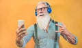 Senior hipster man using smartphone app for creating playlist with rock music - Trendy tattoo guy having fun with mobile phone