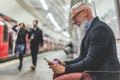 Senior hipster man using smartphone in subway underground - Fashion mature person having fun with technology trends waiting his Royalty Free Stock Photo