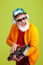 Senior hipster man wearing eyeglasses posing on green background. Tech and joyful elderly lifestyle concept