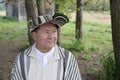 A senior Hispanic man in his seventies wears a traditional Colombian poncho called \